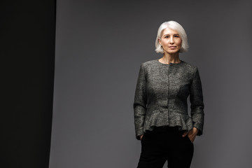 Fototapeta premium Business senior woman in blazer on grey background