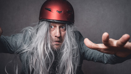 Portrait skuril crazy Mann graue lange Haare mit rotem Helm