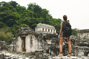 Woman with a backpack beside ancient Mayan ruins