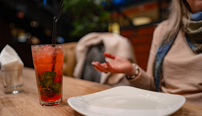 A woman drinks an alcoholic cocktail in a cafe. Close-up of a woman drinking a red cocktail in a cafe. Drinks, people and lifestyle concept-close