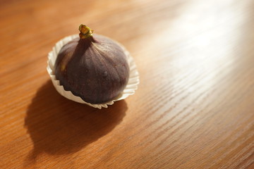 Fototapeta premium Ripe sweet fig in white paper on a wooden table.
