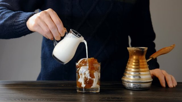 Man pouring cream in iced coffee
