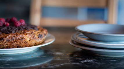 Wide close up of a vegan chocolate cake and the plates to be served on, with copy space.
