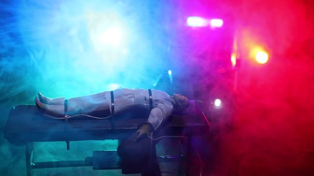 Lethal injection concept. Prisoner handcuffed to death by lethal injection. Creative artwork decoration with scale model on dark with lights.
