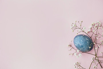 Stylish easter egg and spring flowers on pink paper flat lay, space for text. Modern natural dyed blue easter egg. Happy Easter. Greeting card template