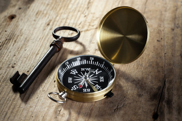 Fototapeta na wymiar old vintage compass near old rusty padlock key lie on old wooden background