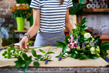 Female florist preparing big bouquet of flowers at the counter