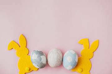 Stylish easter eggs, yellow bunny on pink paper table flat lay, space for text. Natural dyed easter eggs and rabbit decorations. Card mockup. Happy Easter.