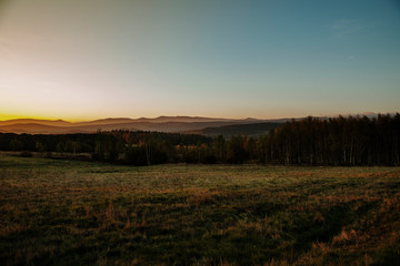 Obraz premium sunrise on the meadow with hills in background