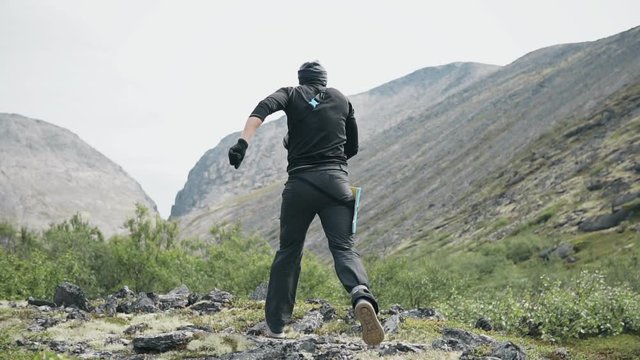  Young man runs up to top of mountain and uplifts his hands as a sign of victory