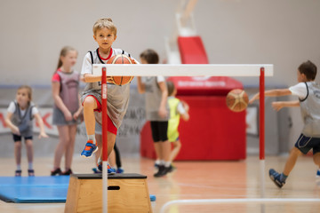 Young boy exercises with a basketball ball in a sports hall © Dziurek