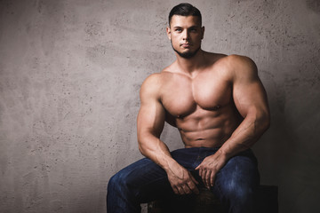 Massive bodybuilder posing beside the concrete wall