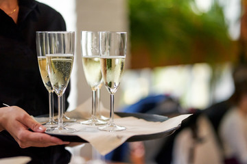 Closeup of glasses of champagne held by waitress during party