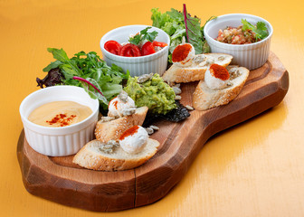 Board with delicious snacks. Guacamole, eggplant with Dor blue, sheep cheese with paprika eggplant puree.