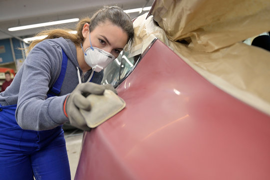 Apprentice working on car body shell in workshop