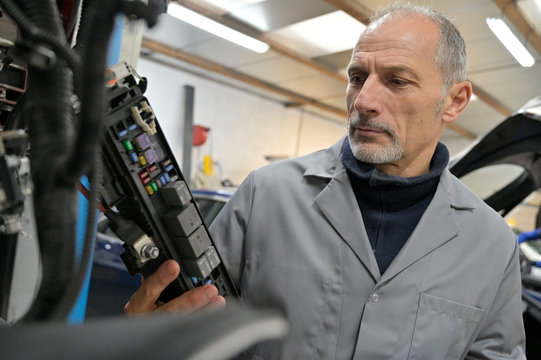 Engineering technician checking vehicle in workshop