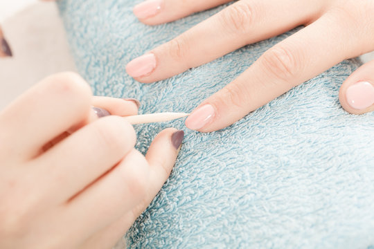 Beautician preparing nails before manicure, pushing back cuticles