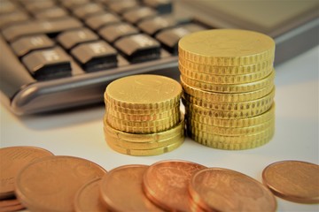 Monedas de euro apiladas, de fondo calculadora