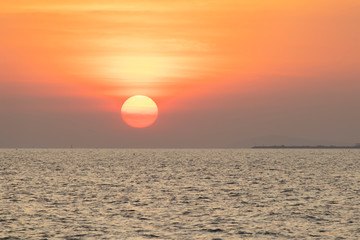 The red sun over the evening sea near the industrial area by the sea