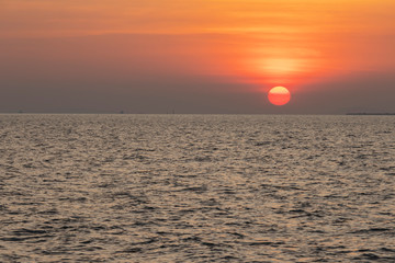The red sun over the evening sea near the industrial area by the sea