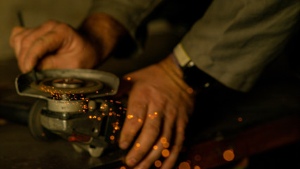 CLOSE UP: Bright sparks fly off the circular disc grinding a metal workpiece.