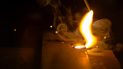 MACRO: Small flame rises from a hot weld burnt into a large piece of metal.