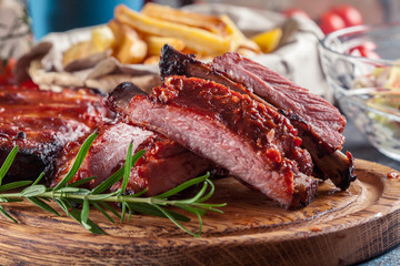 Spicy barbecued pork ribs served with BBQ sauce on chopping board