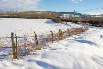 Snow drifts along the road and fence in the countryside