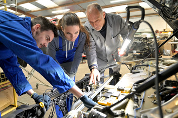 Instructor with trainees working on car engine