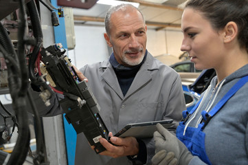 Trainee with mechanics manager working on car technology