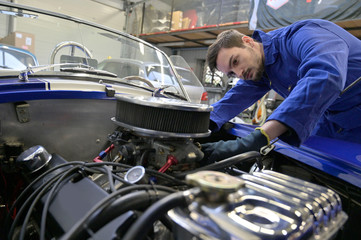 Apprentice working on car engine in workshop