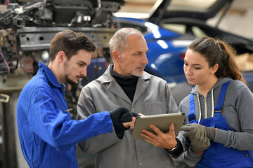 Apprentice with instructor using tablet in workshop
