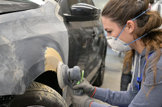 Apprentice working on car body shell in workshop