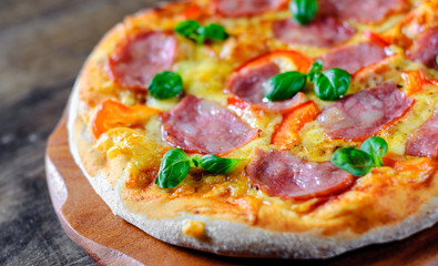 Pizza with Mozzarella cheese, ham, pepper, meat, Tomato sauce, Spices and Fresh Basil. Italian pizza on wooden background