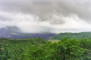 Fototapeta na wymiar Volcano Agung or Gunung Agung on a rainy day. Low clouds over a sacred volcano and jungle. Lava traces on the slopes of the mount. Bali island, indonesia