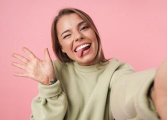 Portrait of beautiful smiling woman waving hand and taking selfie