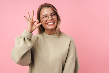 Portrait of young smiling woman winking and gesturing ok sign
