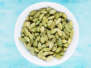 Spice Green Cardamom (Elettaria cardamomum) in a white cup on a blue wooden background