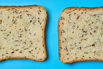 Two square pieces of bread with seeds for toast lies on blue table on kitchen. Top view. Close-up