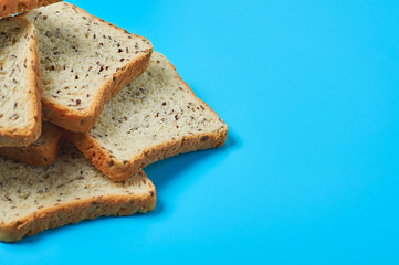 Heap of square pieces of bread with seeds for toast lies on blue table on kitchen. Space for text