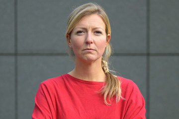 Blond woman in red shirt with arms folded