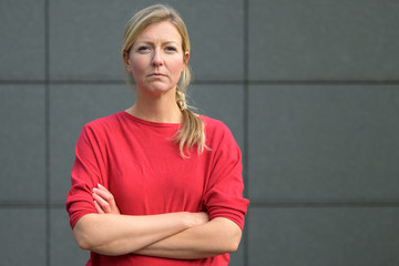 Blond woman in red shirt with arms folded
