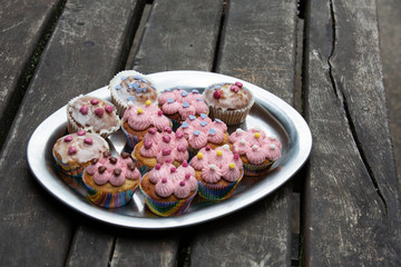 Metal tray on rustic wood table with icing muffins