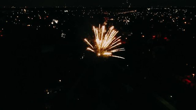 Fireworks in the City Sky. Aerial Drone Scene. City Night Lights. The Camera Rotates in a Semicircle and it is seen how the fireworks explode. 4K footage.