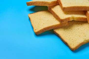 Heap of square pieces of yellow vanilla bread for toast lies on blue table on kitchen. Space for text