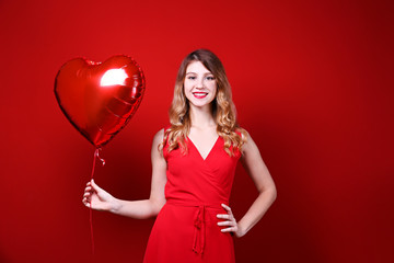 Portrait of young blonde woman posing with helium inflated air balloon. Happy valentine's day concept. Happy female with curled hair over colorful background. Close up, copy space for text.