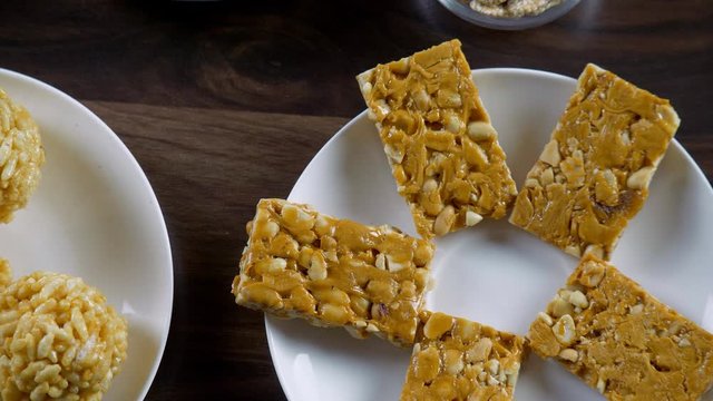 Top view shot of healthy and delicious Lohri items for Lohri celebration in India. Closeup shot of peanuts chikki with murmura ladoo  crispy til gajak  and rewri beautifully plated in ceramic plate...