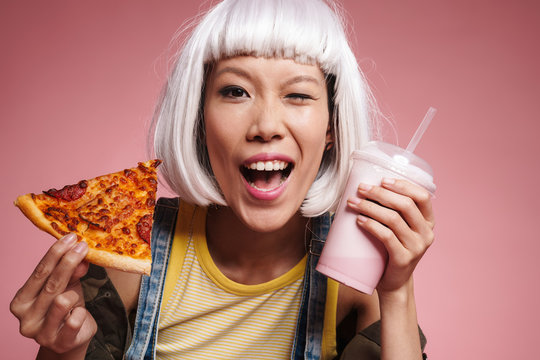 Image of asian girl in white wig drinking milkshake and eating pizza