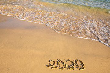2020 summer beach holiday season written on golden sand washed away wave - new season lettering on sand - numbers 2020 year travel vacation sandy wavy water yellow blue azure aquamarine turquoise