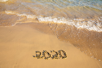 2020 summer beach holiday season written on golden sand washed away wave - new season lettering on sand - numbers 2020 year travel vacation sandy wavy water yellow blue azure aquamarine turquoise